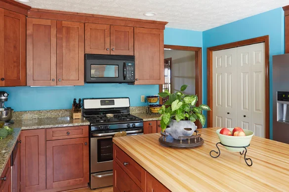 Cherry cabinet kitchen with butcher block island and bold blue accent walls